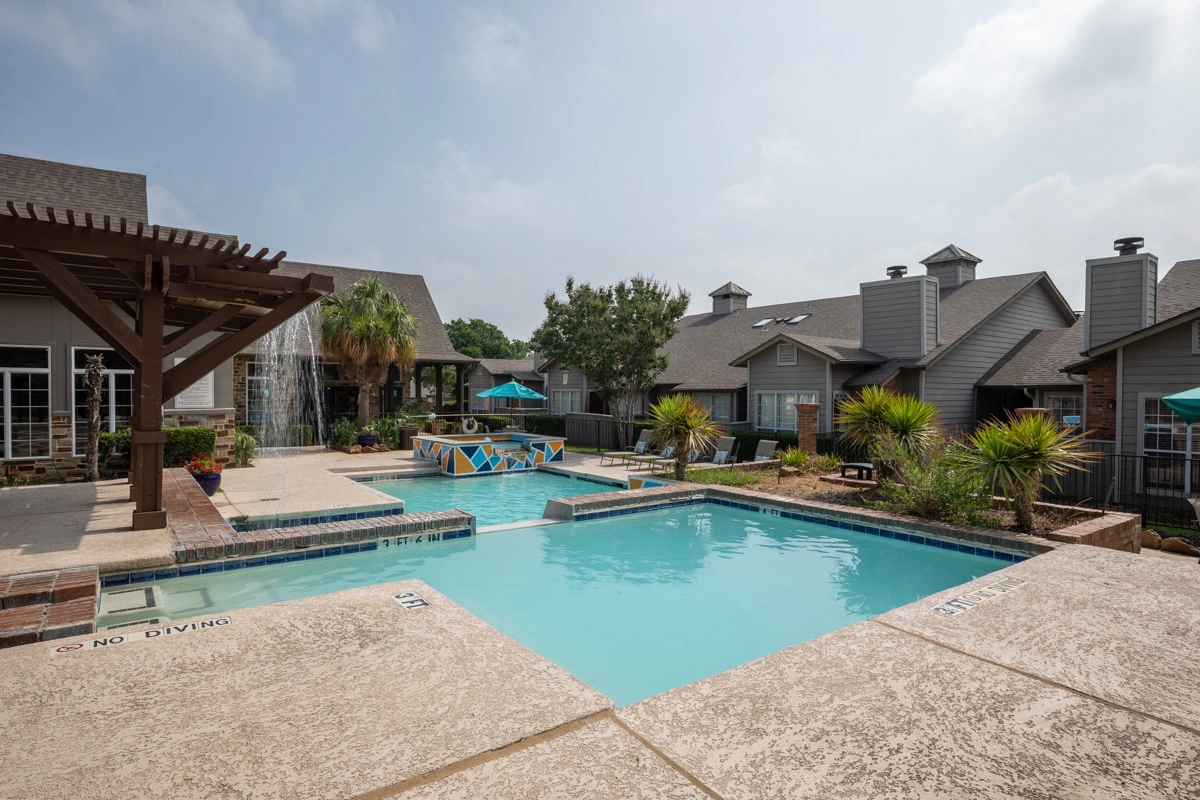 Outdoor pool area at Village Green of Bear Creek apartments