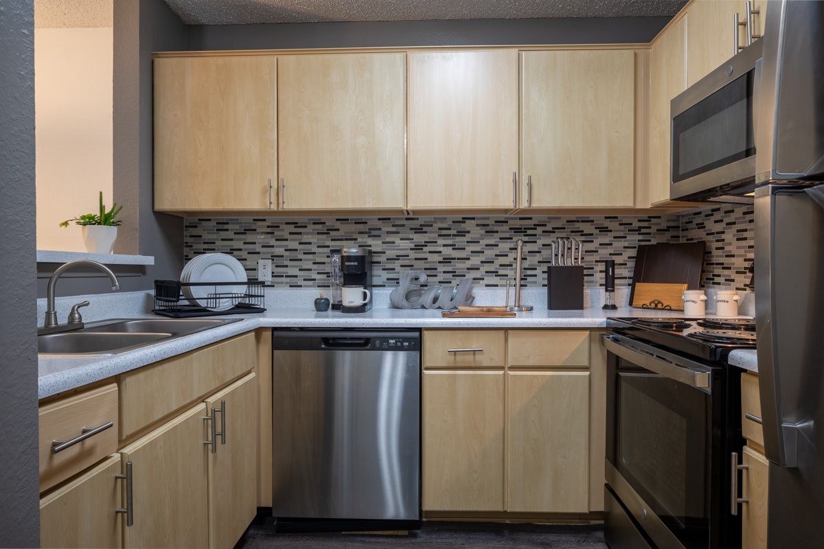 Luxury kitchen with white cabinets, granite countertops, and stainless steel appliances at our apartments for rent in Euless, TX