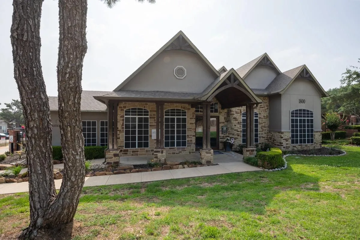 Clubhouse exterior and manicured grounds at Village Green of Bear Creek in Euless, Texas