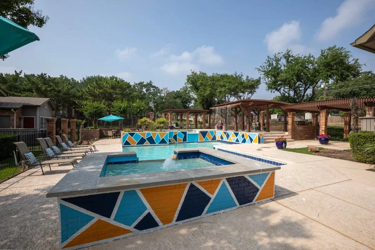 Sparkling pool with water feature and sun loungers at Village Green of Bear Creek in Euless, Texas